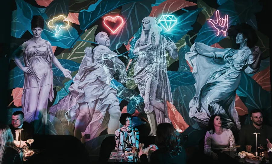 Guests at TOGA in front of the large mural with neon symbols