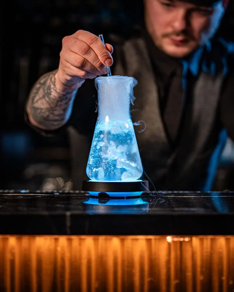 Bartender preparing a cocktail in a blue carafe at the TOGA bar