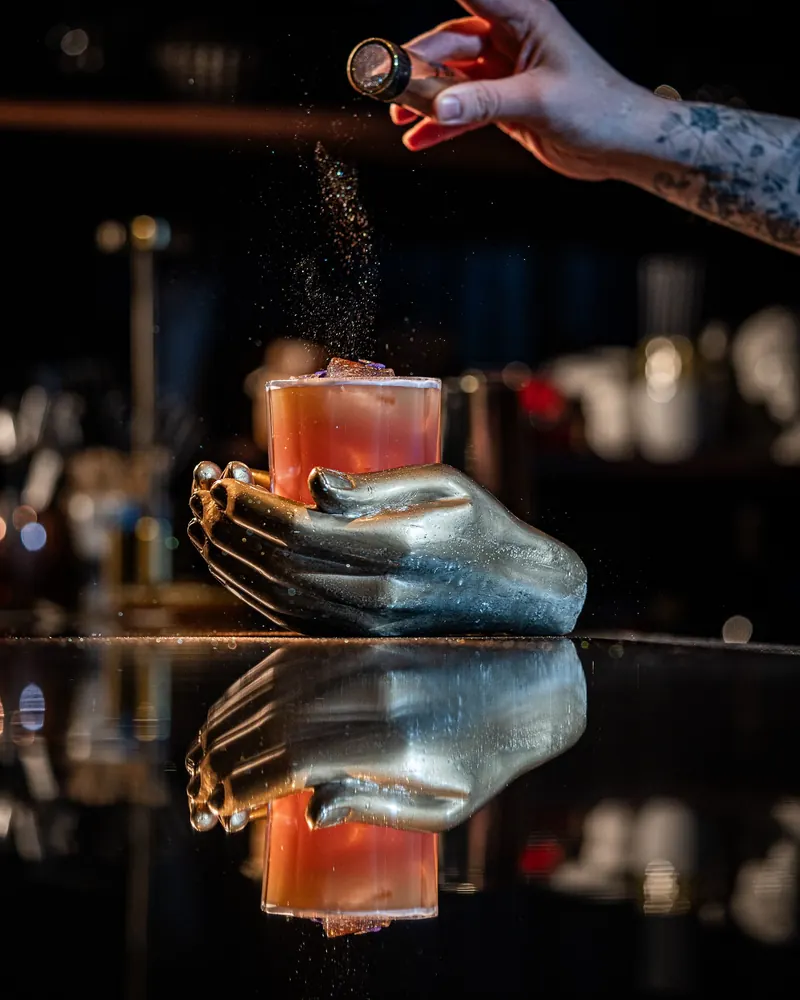 A cocktail being finished with a fine garnish behind the TOGA bar