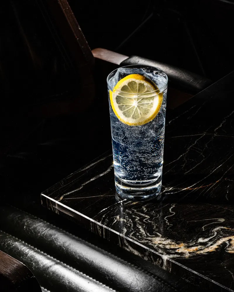 Highball with a lemon slice on a black marble table at TOGA